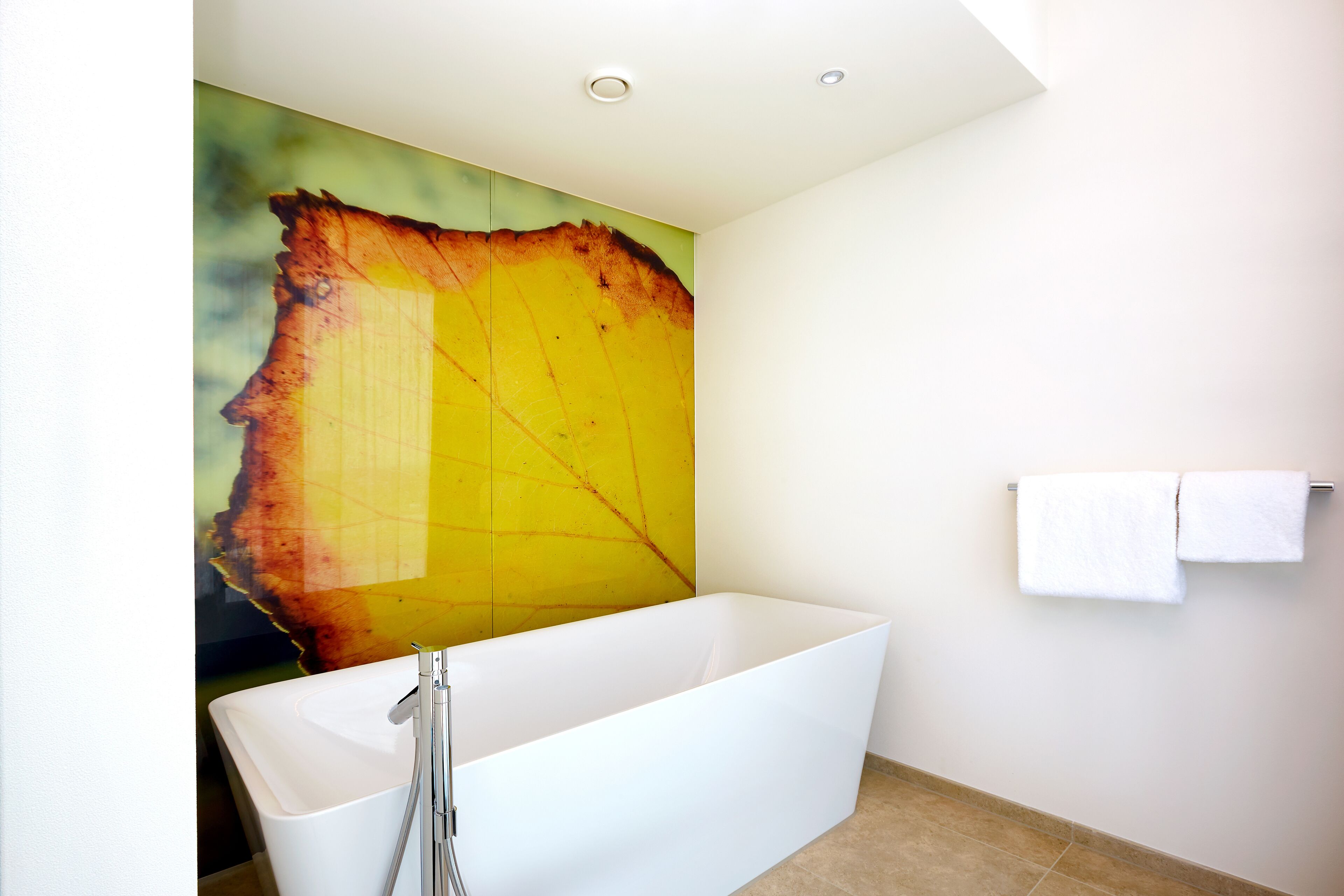 A modern bathroom with a large bathtub, a wall-mounted towel rack, and a large abstract painting.