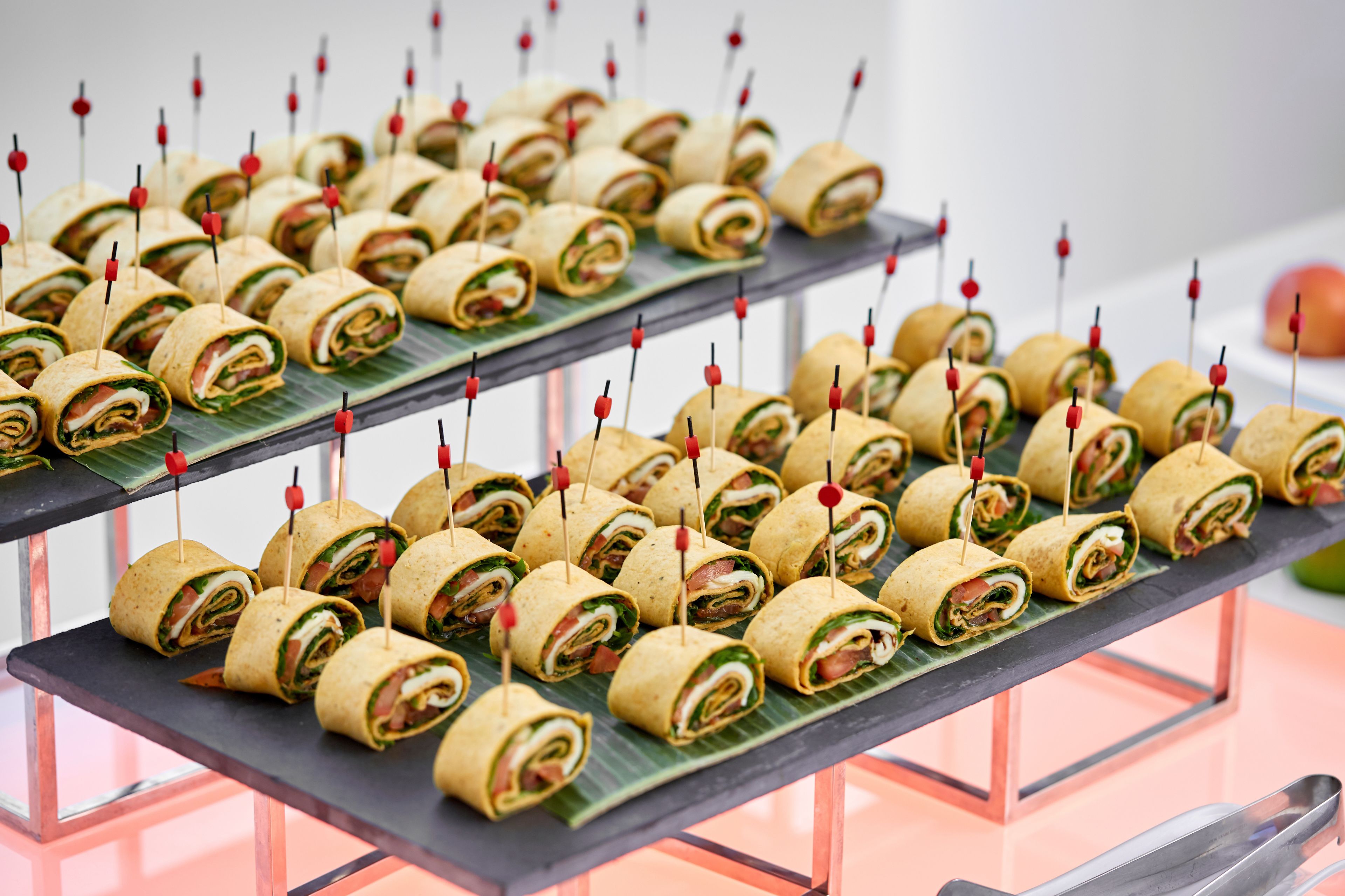 A buffet table with neatly arranged food items, each secured with a toothpick.