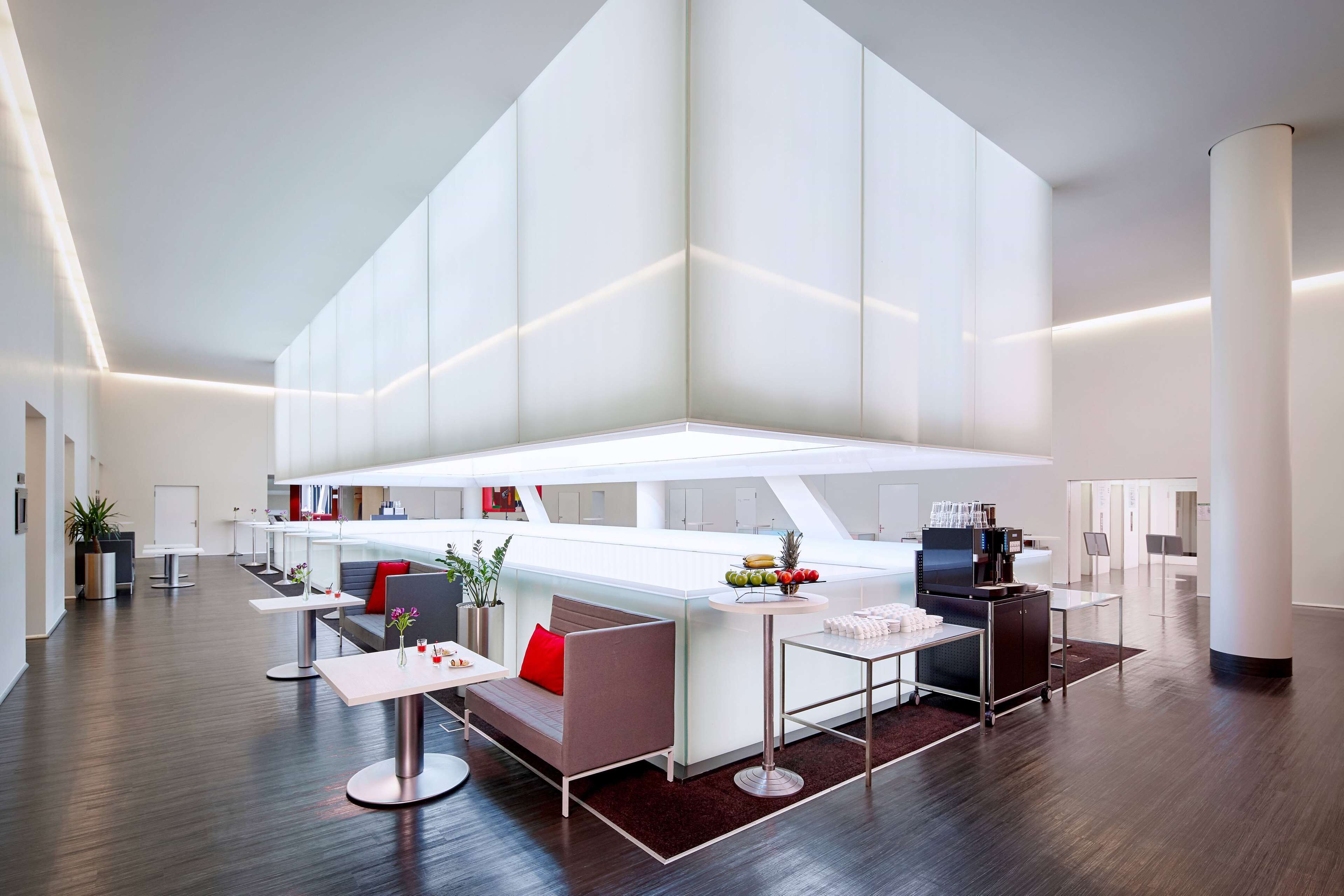 A modern hotel lobby with a central bar area, seating arrangements, and a high ceiling.