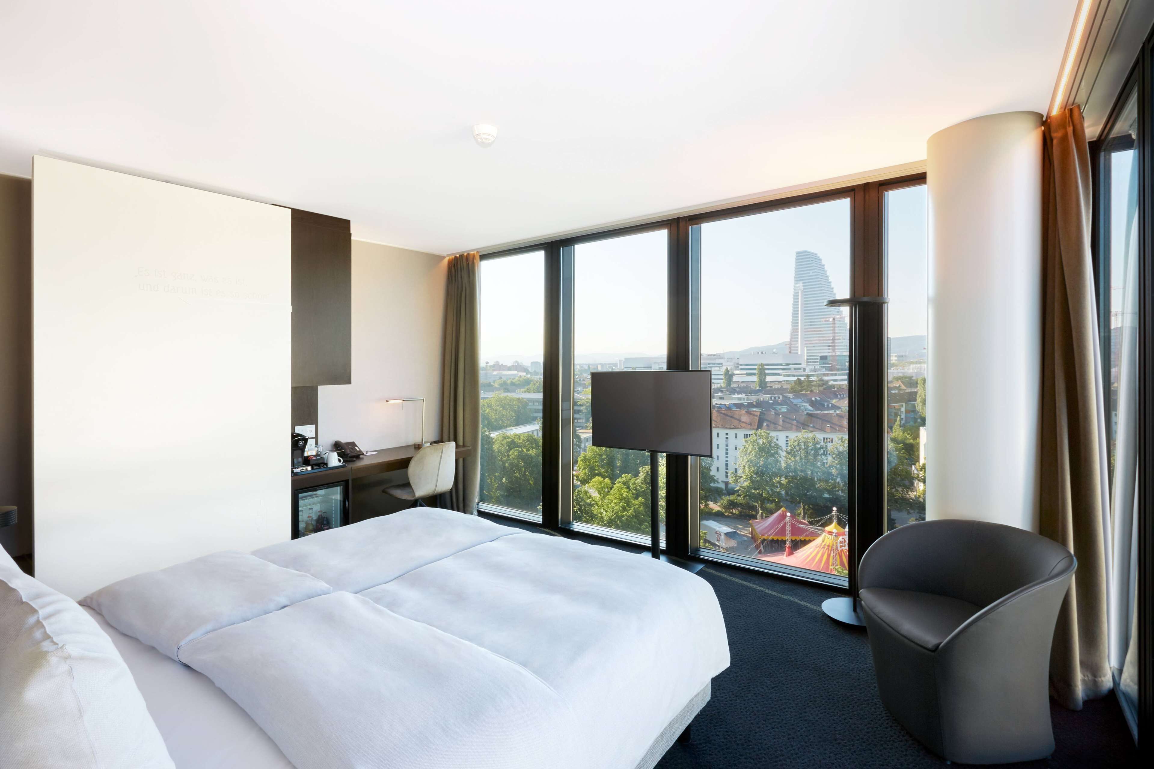 Une chambre d’hôtel avec un grand lit, un bureau avec une lampe, une chaise et un téléviseur.