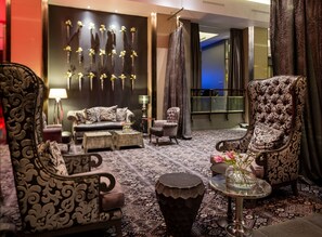 Uma sala de estar luxuosa com móveis ornamentados, um tapete estampado e um painel decorativo.