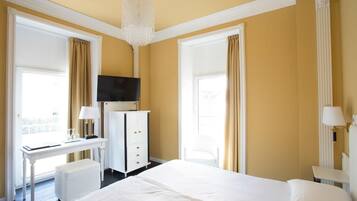 Una camera d'albergo con un letto grande, una scrivania, una sedia, una televisione e un lampadario.