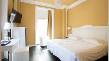 Ein Hotelzimmer mit Bett, Schreibtisch mit Computer, Stuhl und Fernseher.