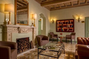 A room with a fireplace, bookshelves, and leather chairs.