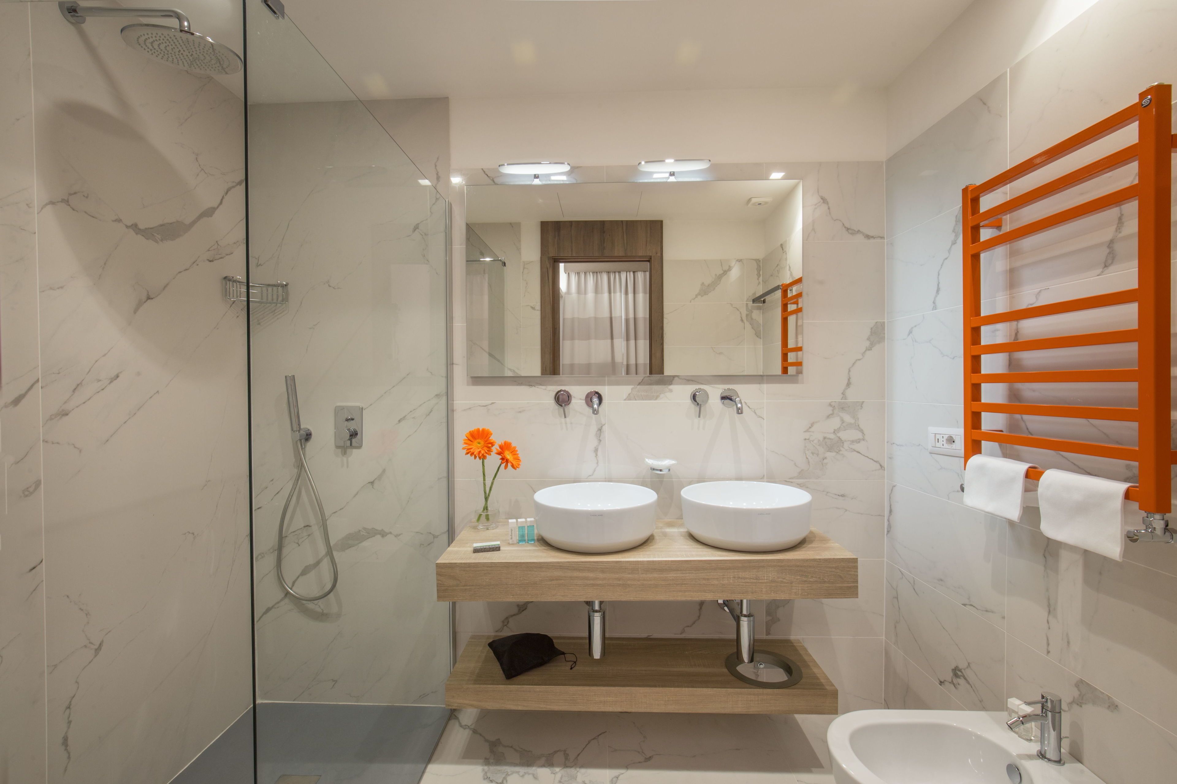 A modern bathroom with two sinks, a shower, and a vanity with a mirror.