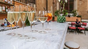 Una zona de bar con varios vasos de bebidas sobre una barra de mármol.