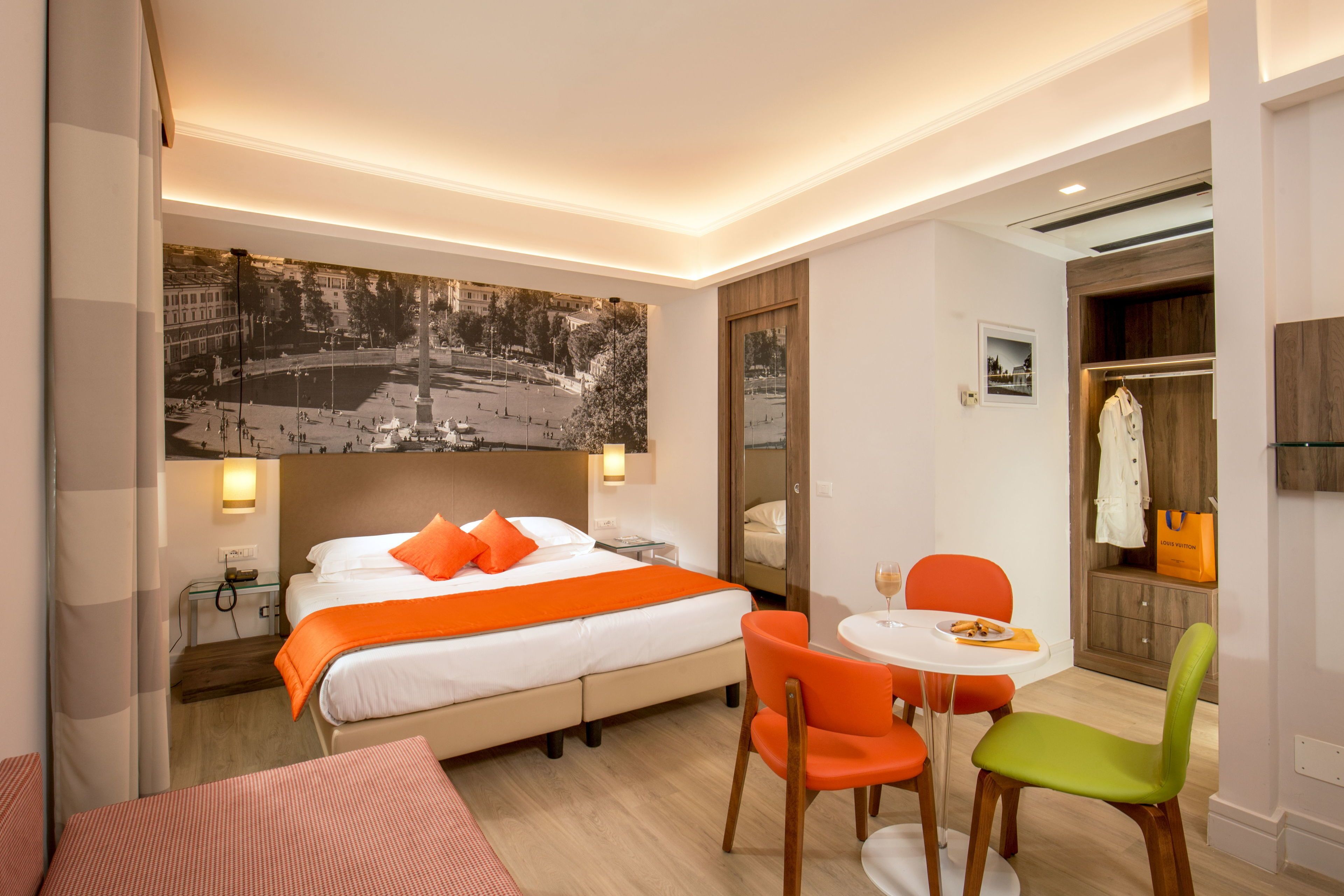 Une chambre d’hôtel comprenant un lit, un bureau, deux chaises, une petite table et un grand tableau accroché au mur.