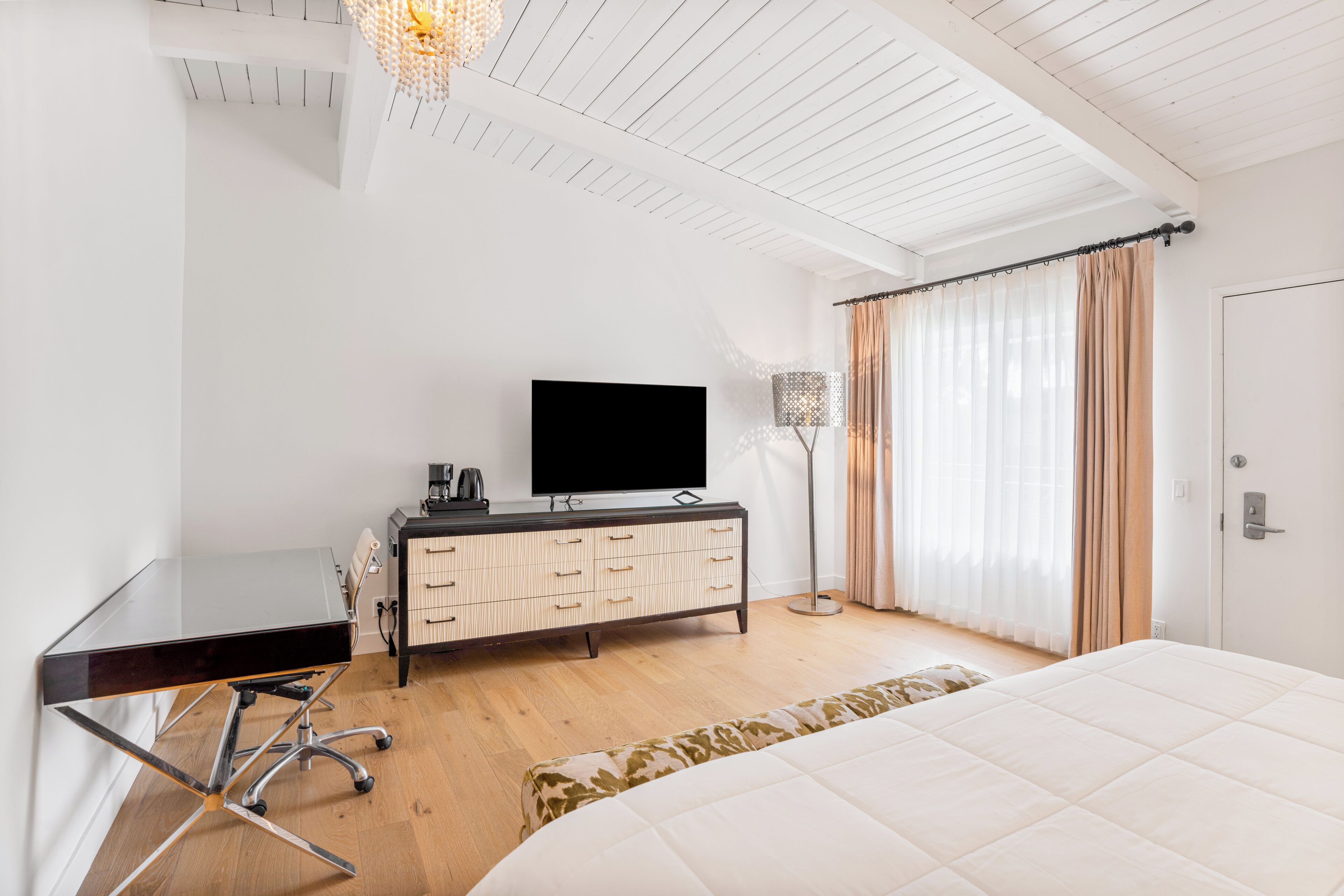 A modern hotel room with a flat-screen TV, a desk, and a bed.