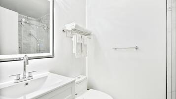 Een moderne badkamer met een wit wastafelmeubel, toilet en een douchecabine van glas.