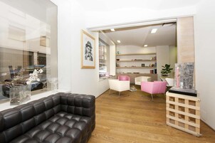 A modern living room with a leather sofa, white chairs, a wooden coffee table, and a glass display case with flowers.
