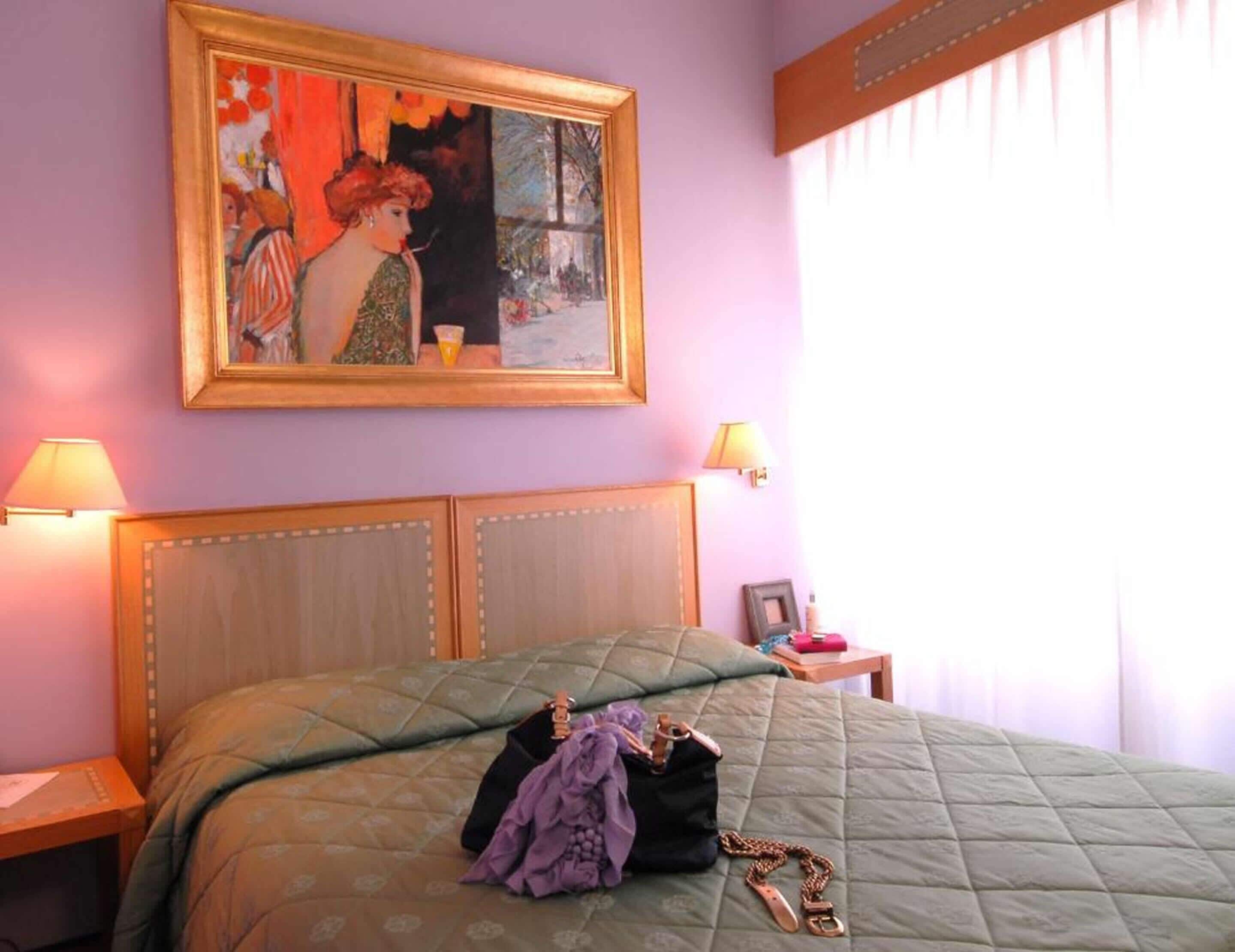 Una camera da letto con un letto grande, due lampade ai lati, un quadro incorniciato e un comodino con una lampada e una cornice.