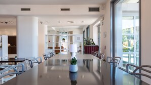 A modern dining area with a long table, white chairs, and a potted plant.