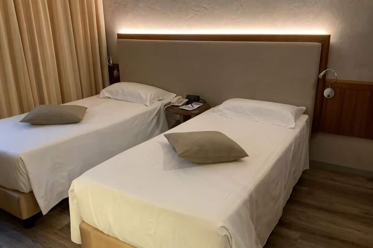 Two single beds with headboards, bedside tables, and a nightstand with a lamp.
