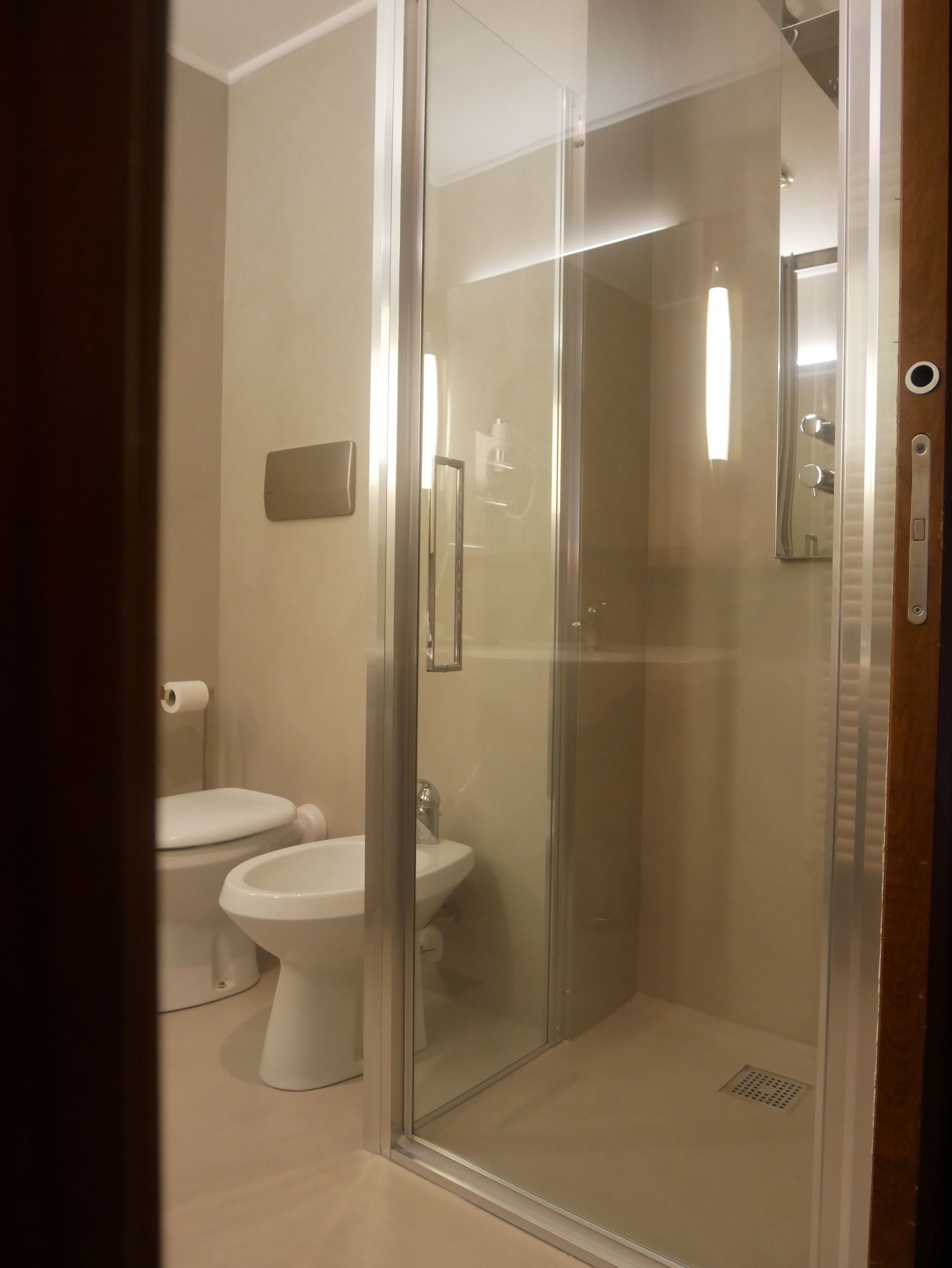 Un baño moderno con ducha de vidrio, inodoro y lavamanos.