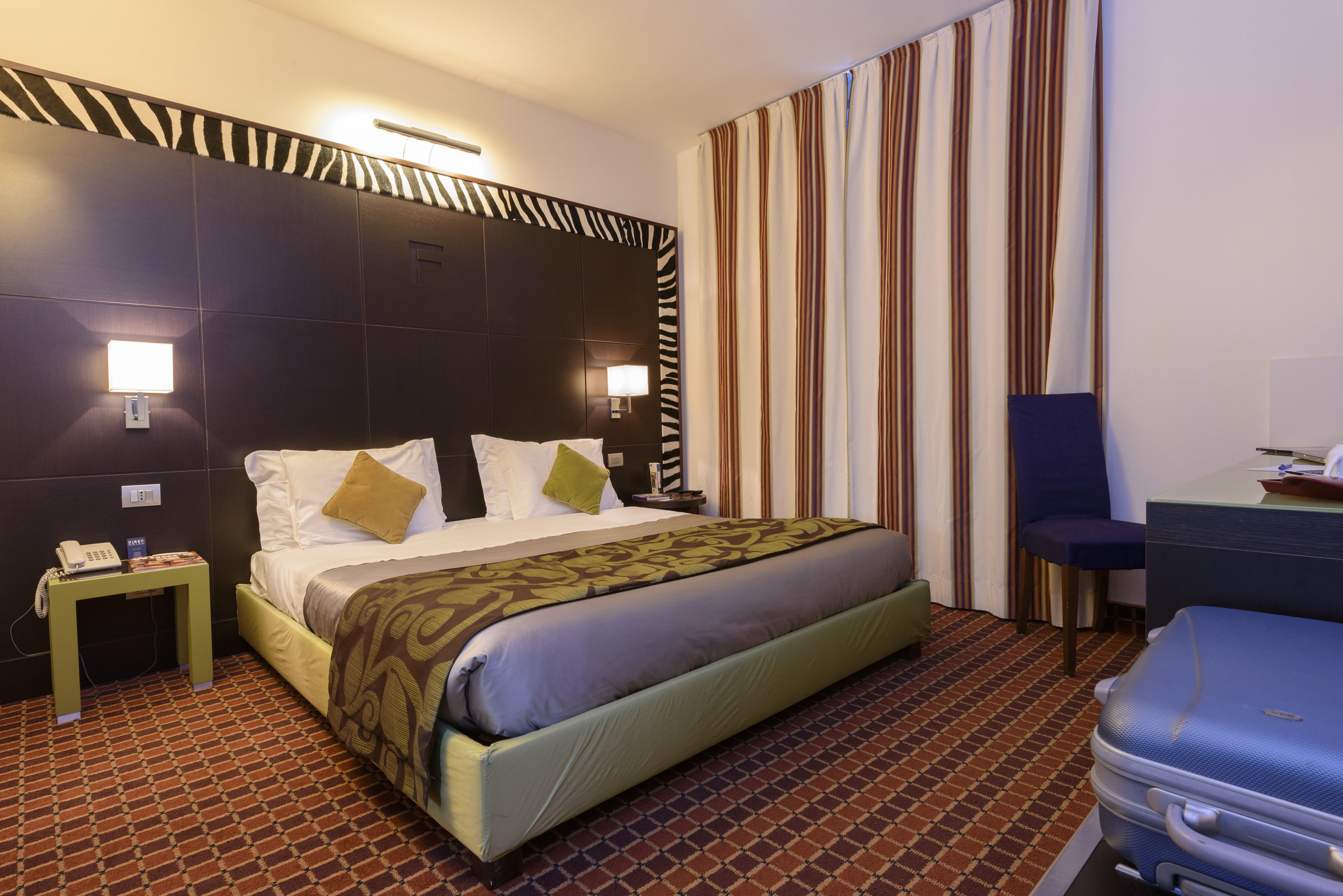 A hotel room with a large bed, a desk, and a chair.