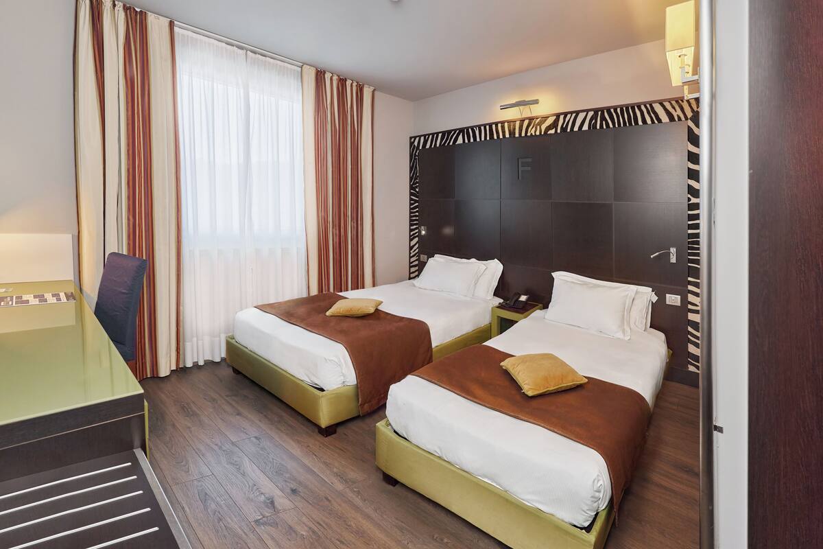 A hotel room with two beds, a desk, and a chair.