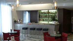 A bar area with a checkered floor, red bar stools, and a bar counter with various bottles.