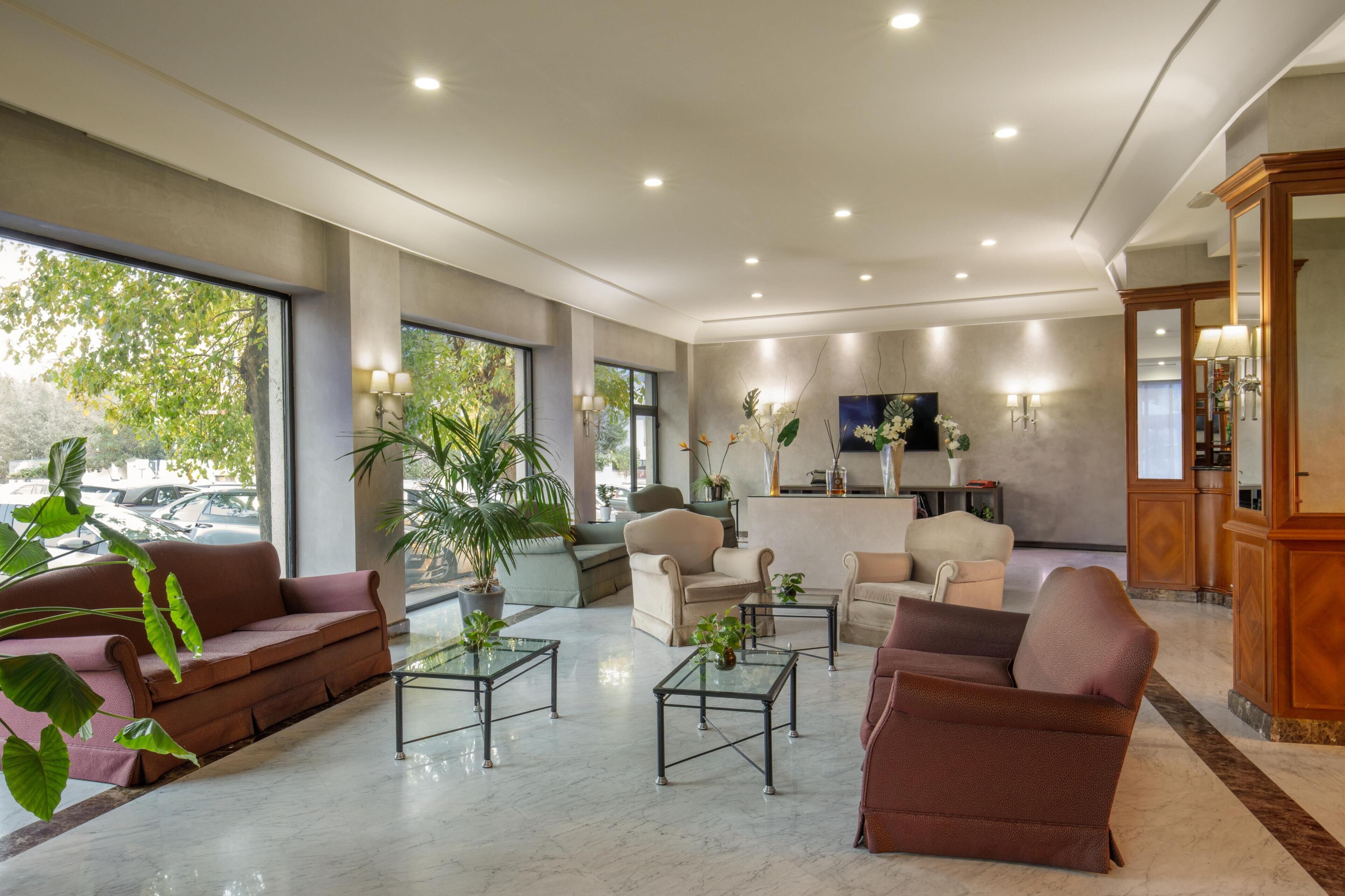 A spacious lobby with a sofa, armchairs, a coffee table, and a reception desk.