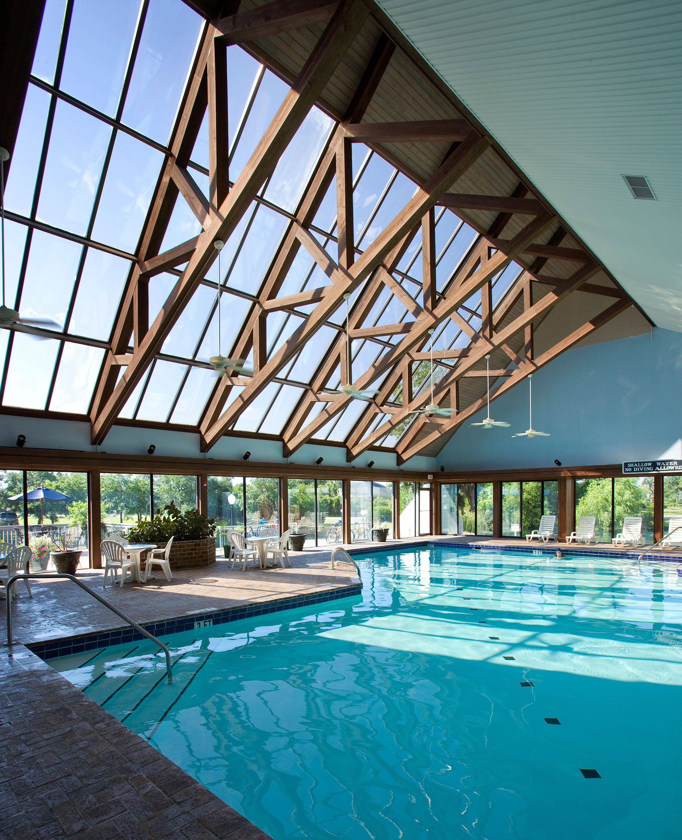 An indoor swimming pool with a high ceiling and large windows.