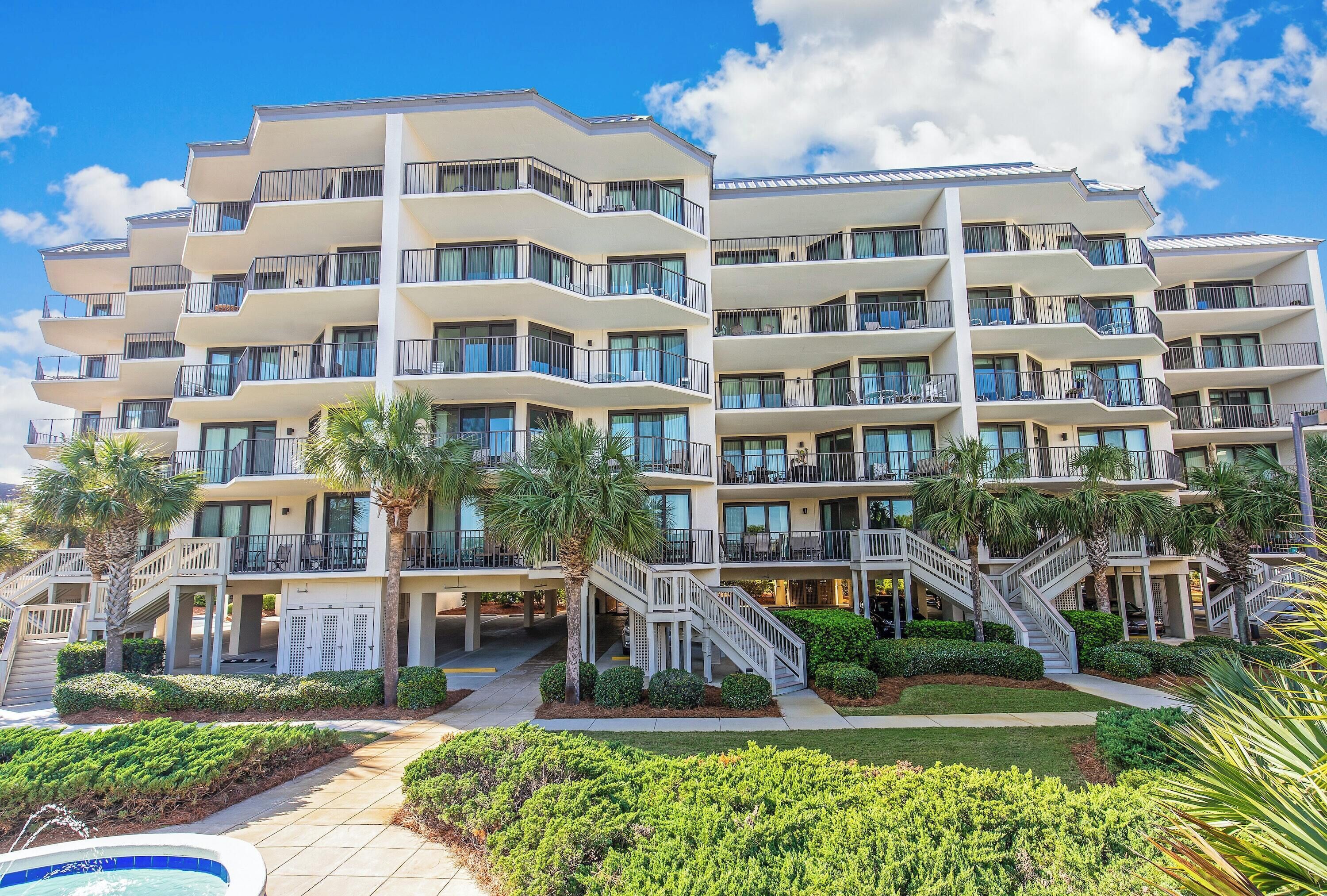 A multi-story hotel with balconies, a swimming pool, and palm trees.