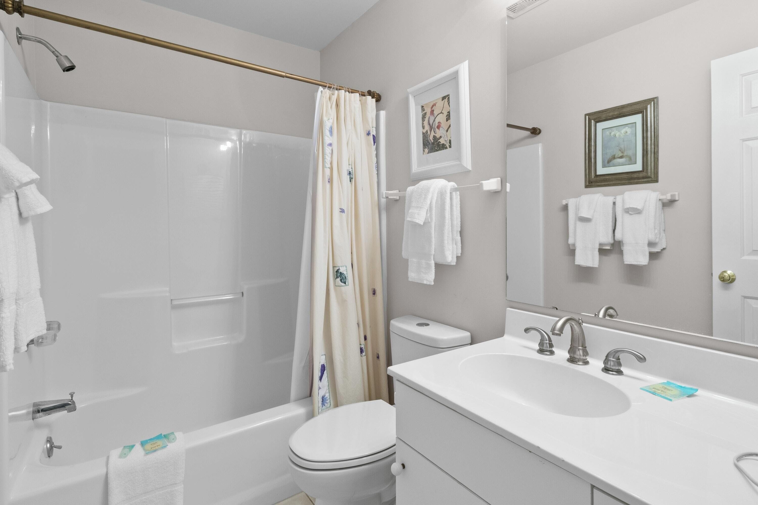 A bathroom with a bathtub, toilet, sink, and shower curtain.