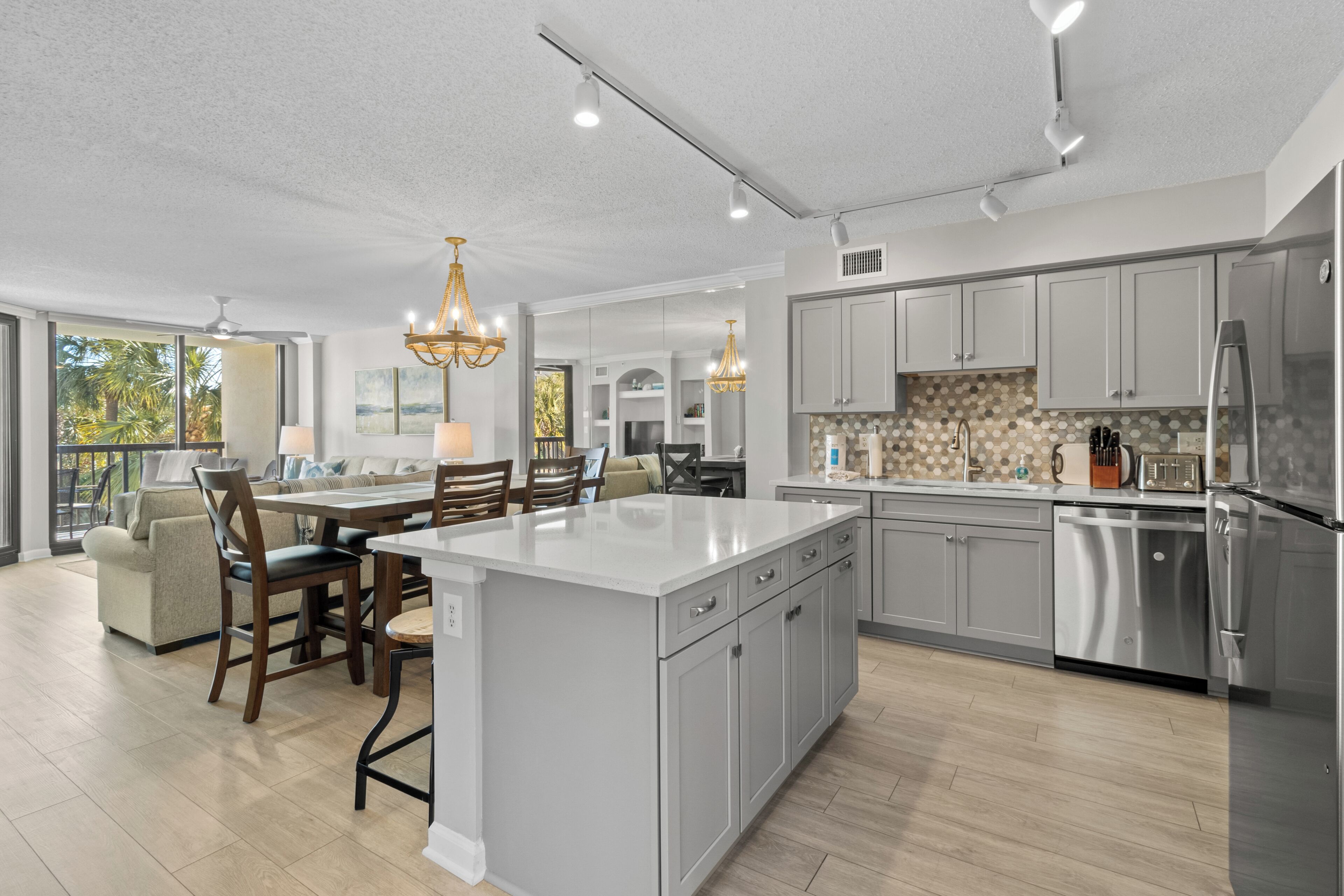 A modern kitchen with a central island, stainless steel appliances, and a dining area with a view.