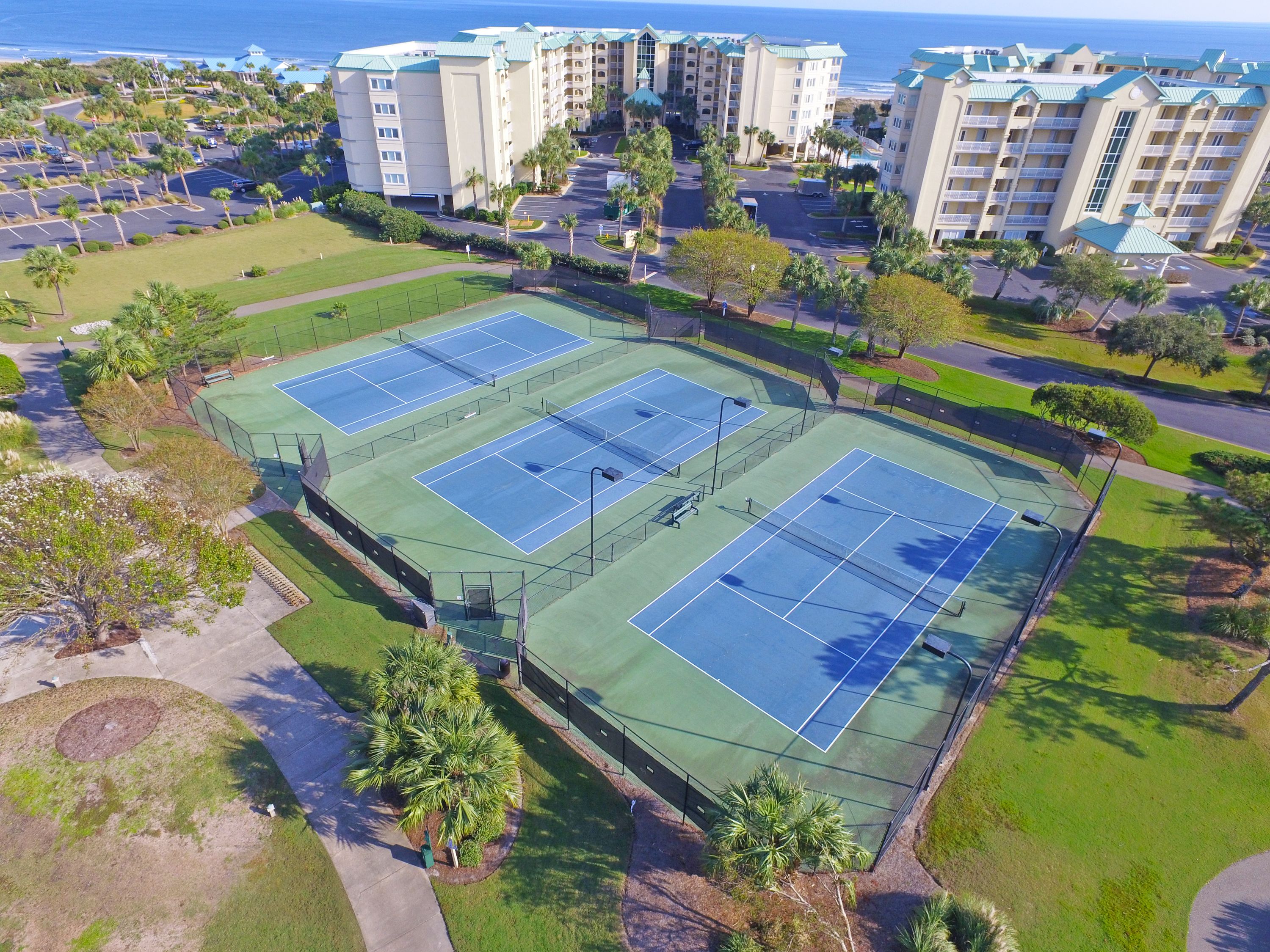 Un hotel de varios pisos con un complejo de canchas de tenis.