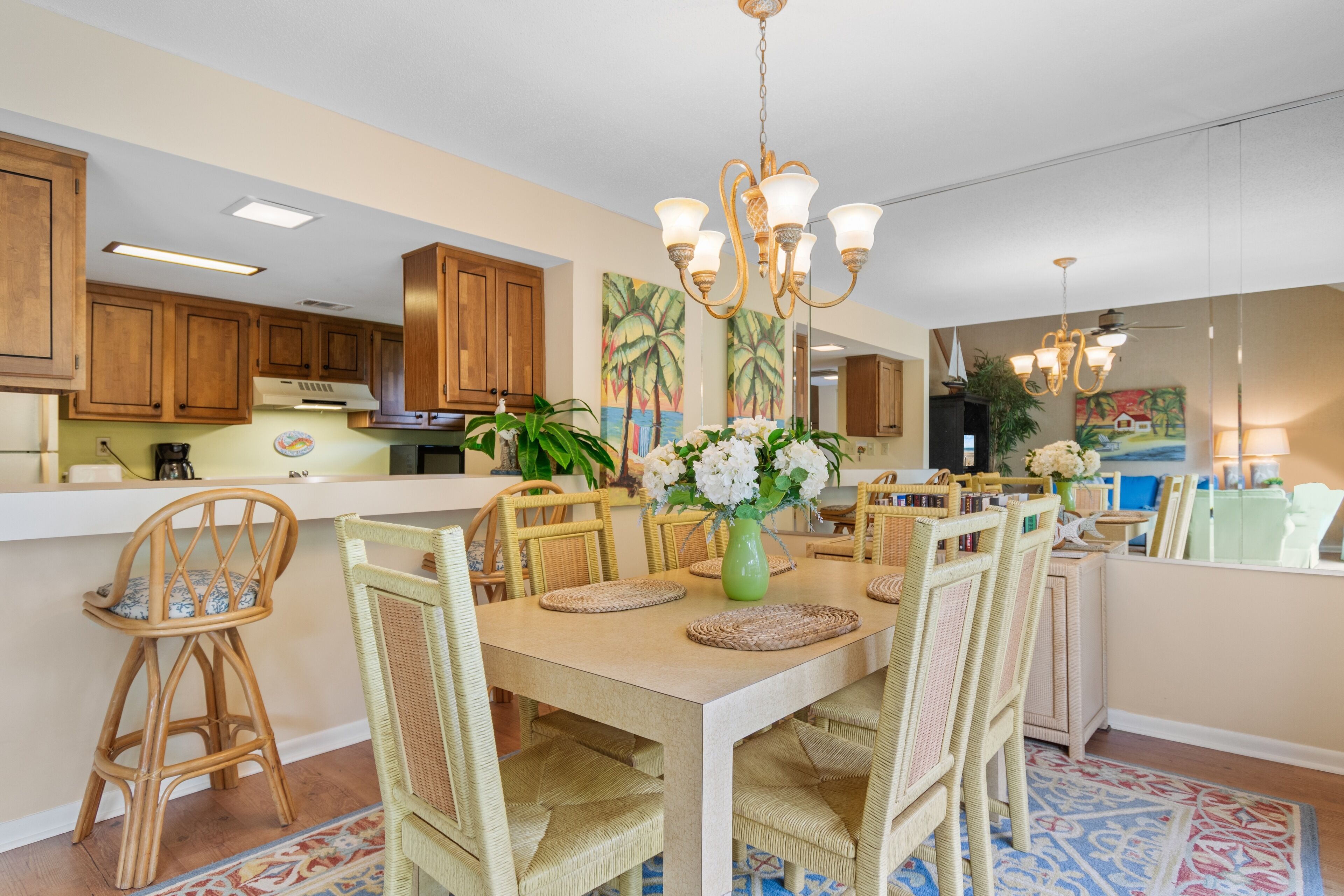 A spacious kitchen with wooden cabinets, a central island, and a dining area with wicker chairs and a table set for four.