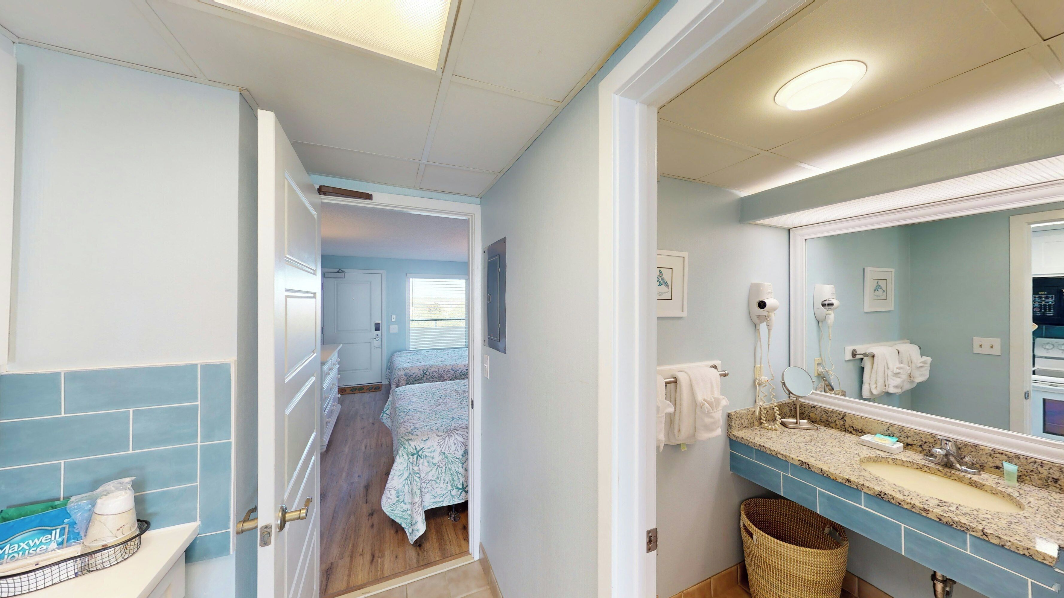 Une salle de bain équipée d’un lavabo, d’un miroir et d’un sèche-cheveux.