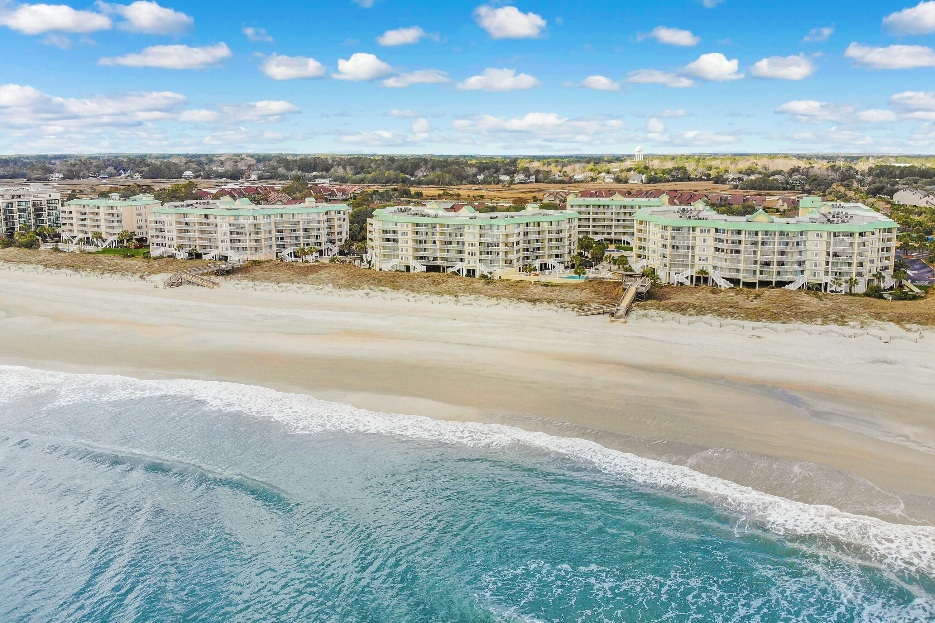 A beachfront hotel with multiple buildings, a sandy beach, and ocean waves.