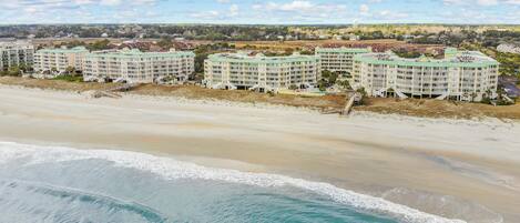 A beachfront hotel with multiple buildings, a sandy beach, and ocean waves.