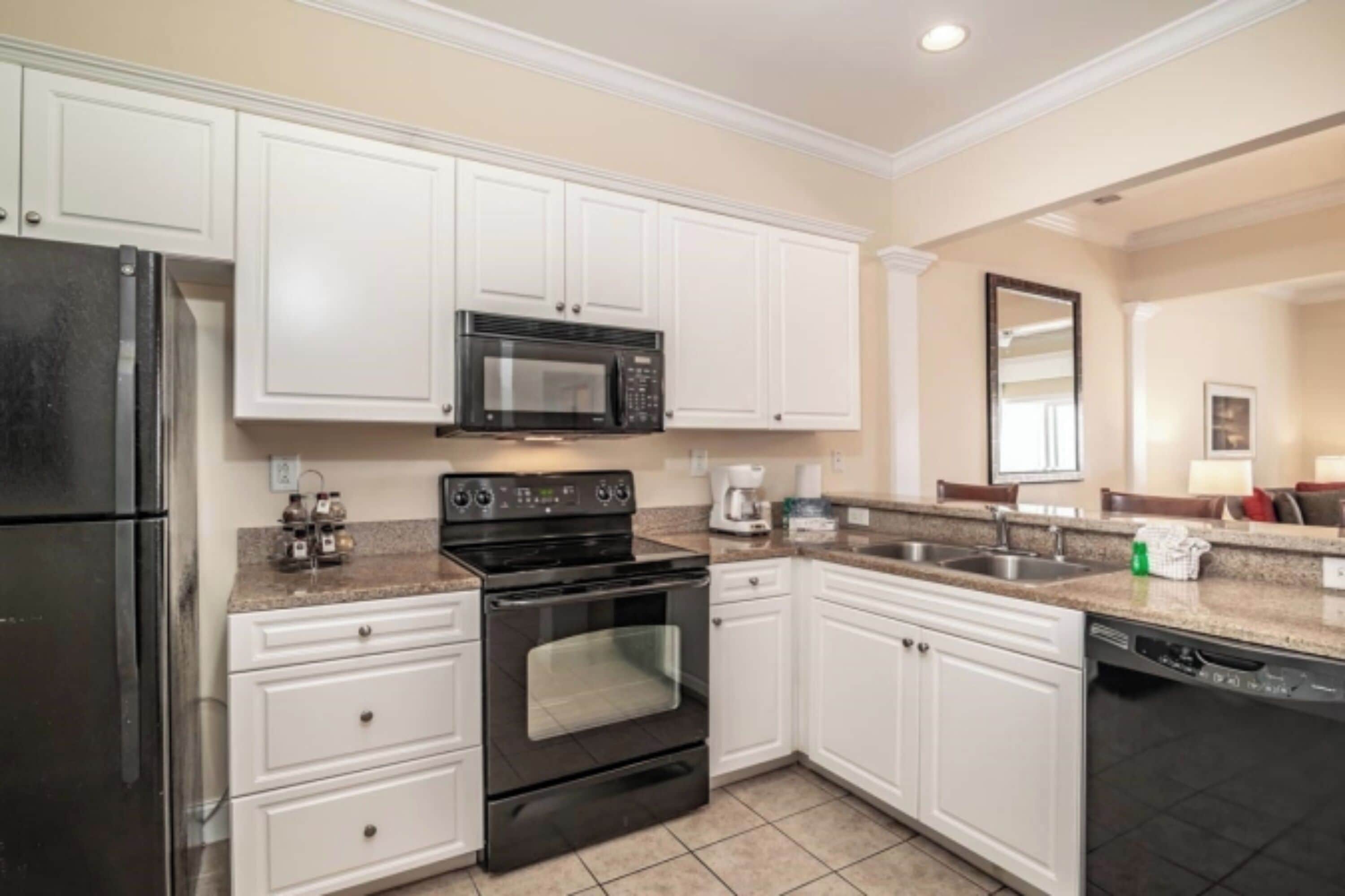 A modern kitchen with white cabinets, a black stove, a microwave, and a dishwasher.