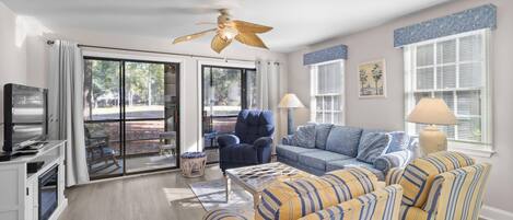 Una sala de estar con sofá, sillones, televisión y ventilador de techo.