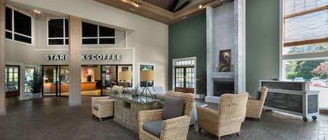 Un amplio vestíbulo con el letrero de Starbucks Coffee, muebles de mimbre, chimenea y ventanas grandes.