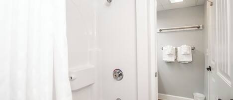 A bathroom with a shower, toilet, and towel rack.