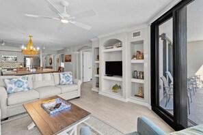 A modern living room with a sofa, coffee table, and TV stand. - Litchfield Beach & Golf Resort (Pawleys Island)