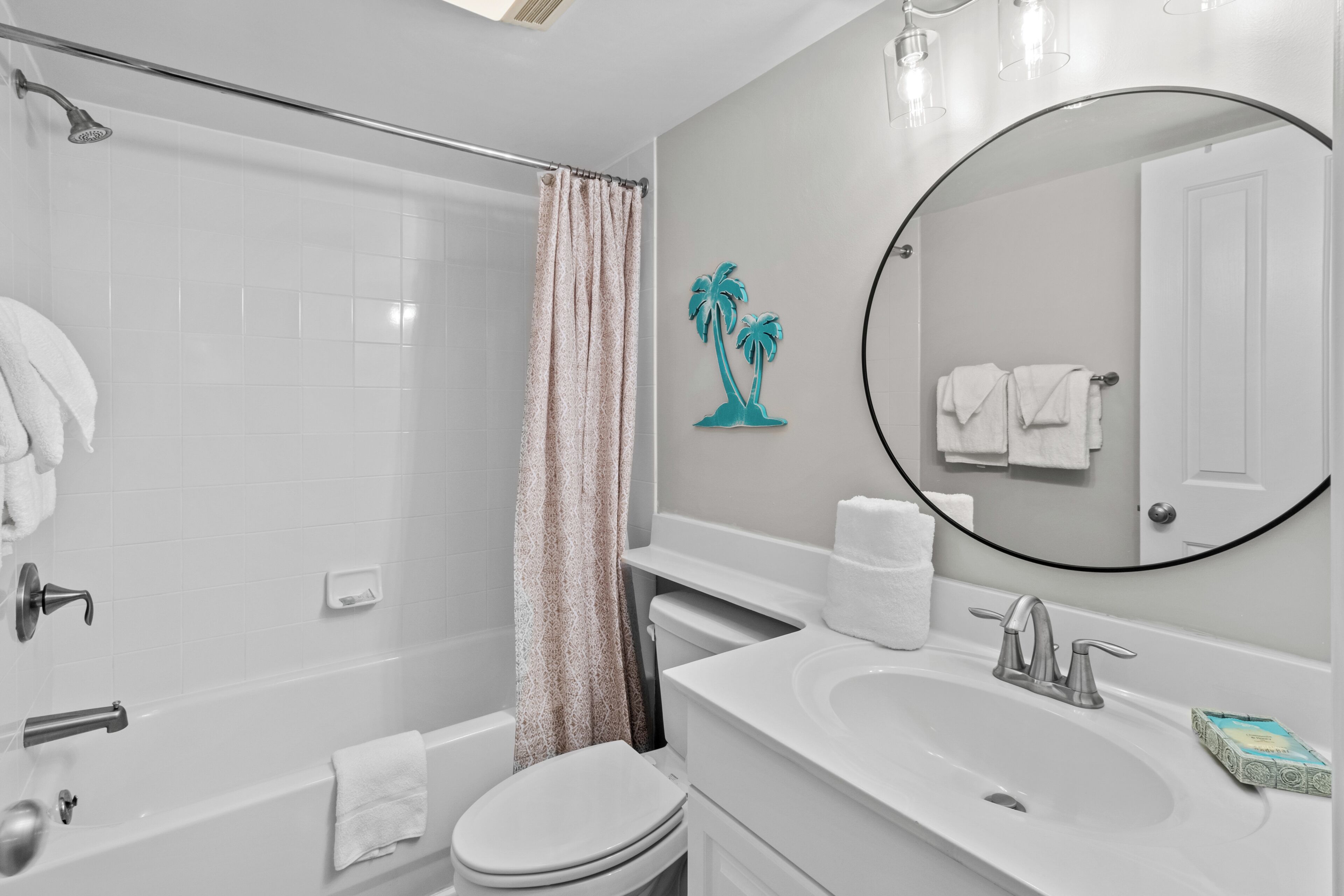 A bathroom with a shower, toilet, sink, and a mirror.