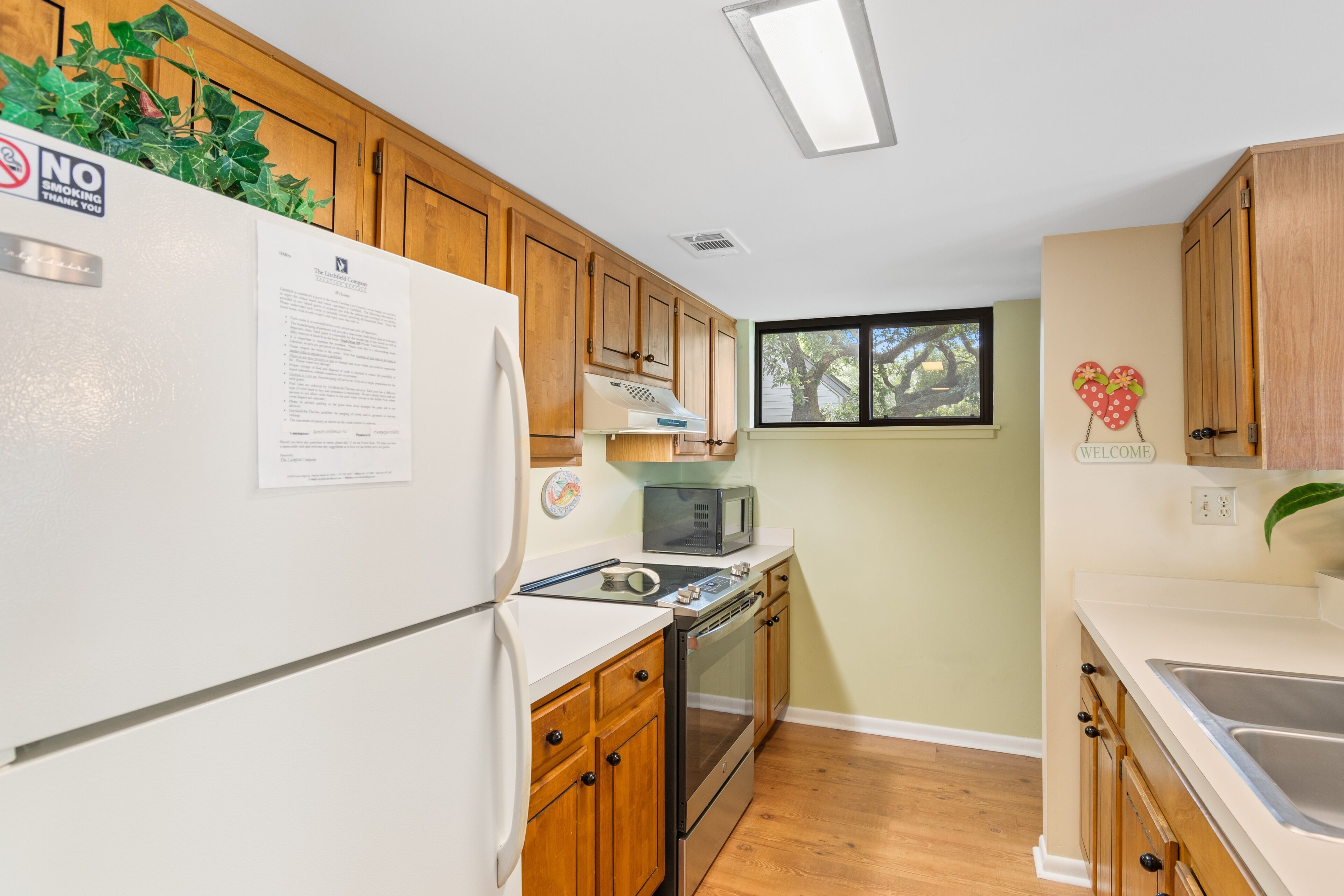 A compact kitchen with wooden cabinets, a white refrigerator, a microwave, and a stove.