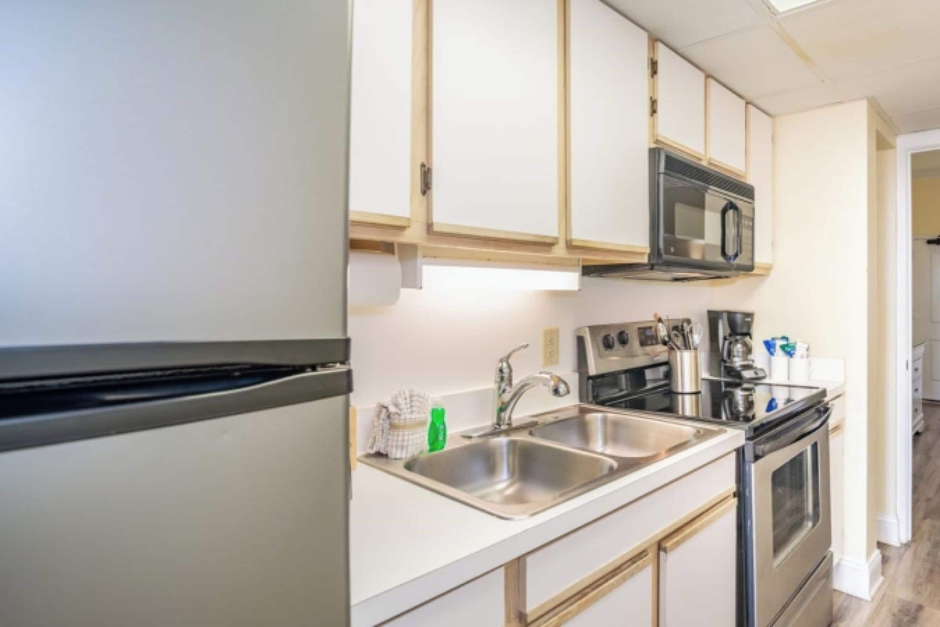A modern kitchen with stainless steel appliances, a double sink, and wooden cabinets.