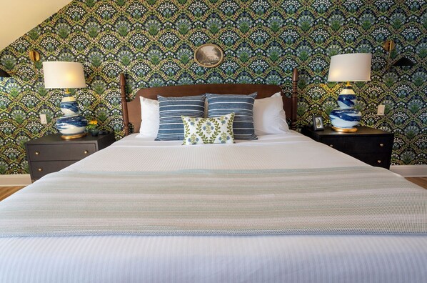 A bed with a headboard, two bedside tables with lamps, and a patterned wallpaper. - Breakwater Inn (Kennebunkport)
