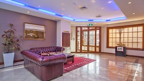 A lobby with a leather sofa, a large mirror, and a reception desk. - Hotel Northbridge (Perth)