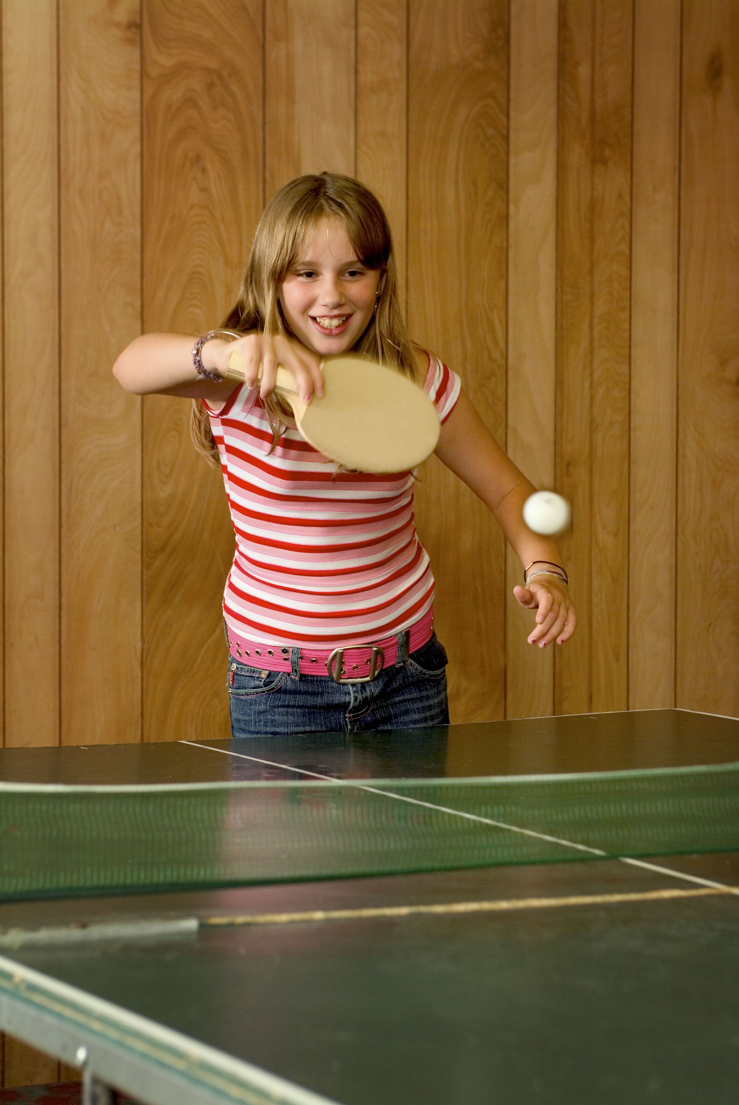 Iemand speelt tafeltennis in een kamer met houten wanden.
