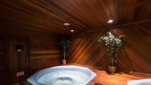 Ein Holzblock-Interieur mit Whirlpool, Holzwänden und einer Decke mit Holzbalken.