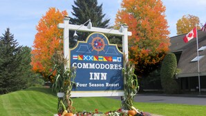 Schild für das Commodores Inn, ein Four Seasons Resort, mit einer Steinmauer und Blumenbeet im Vordergrund.