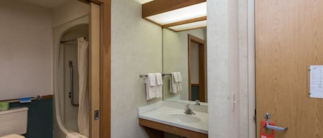 A bathroom with a toilet, shower, and sink.