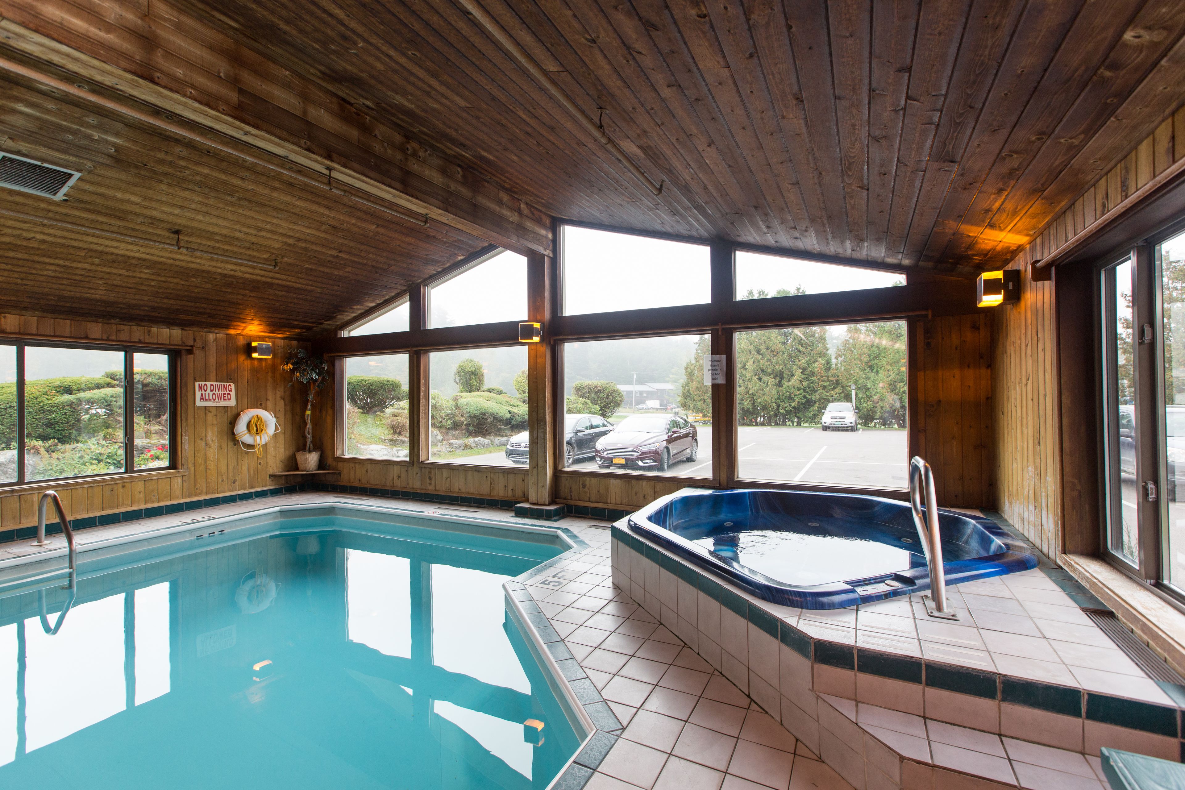 Una piscina interior con hidromasaje, techo de madera y amplios ventanales que ofrecen vistas al exterior.