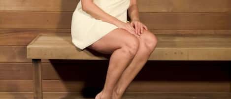 Una persona sentada en un banco de madera en una habitación con paredes de madera.