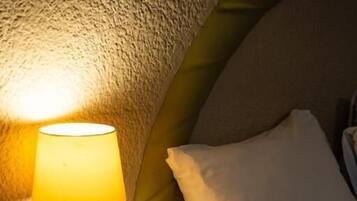 Una habitación de hotel con una lámpara de noche, una taza de café, un bloc de notas y un teléfono en la mesita de noche.