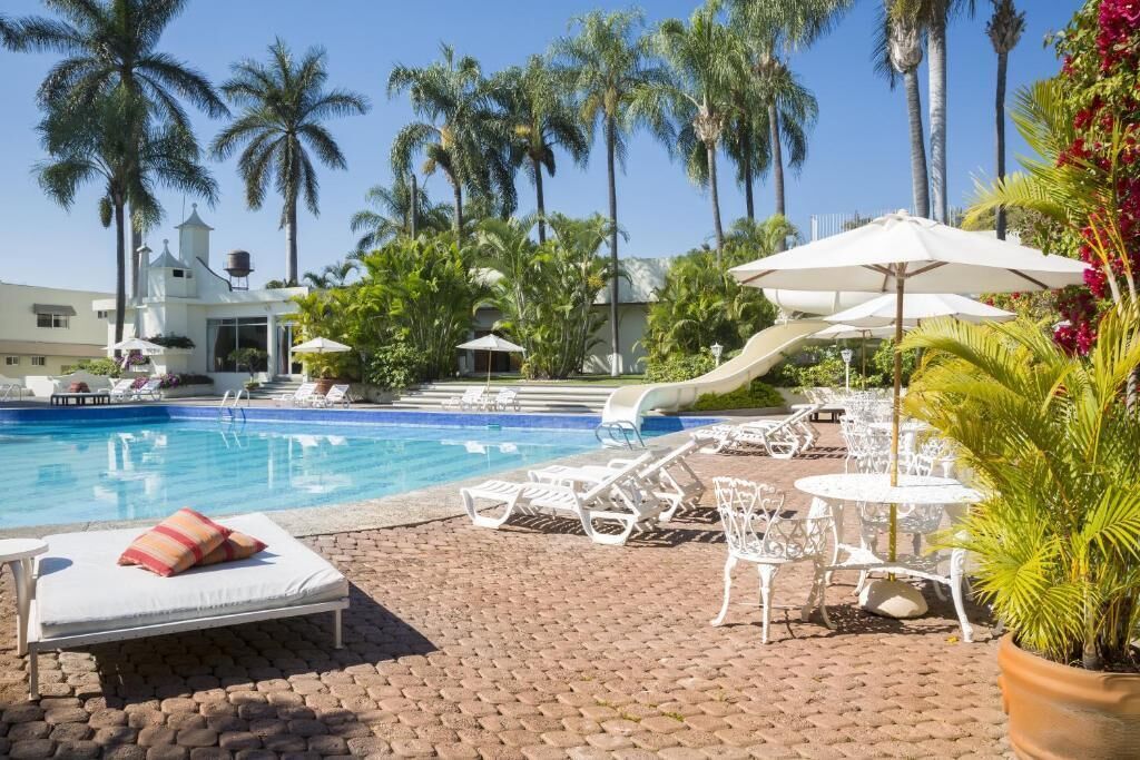 A pool area with lounge chairs, umbrellas, and a slide.