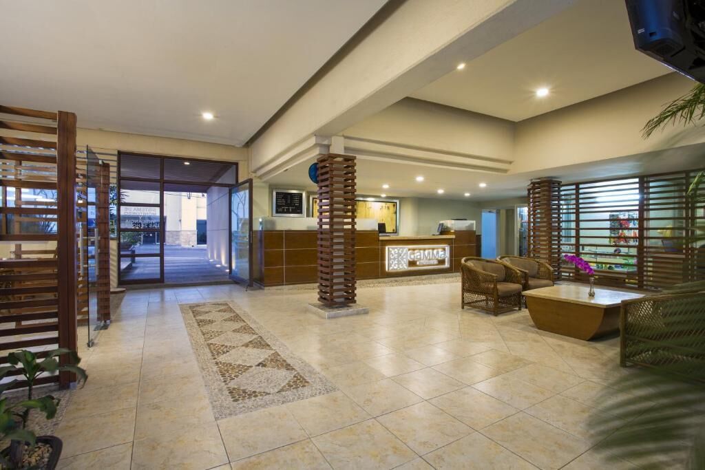 Un hall de hotel con mostrador de recepción, zona de estar y un ventanal grande.